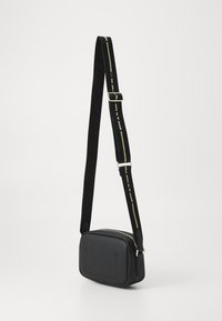 Crna teksturirana torba za preko tijela pravokutnog oblika, s čvrstom naramenicom s zlatnom naglaskom i zatvaranjem na patentni zatvarač.