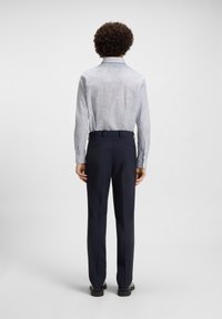 Lichtblauw en wit gestreept overhemd met lange mouwen en een puntig kraag, gecombineerd met donkerblauwe pantalon, gezien vanuit de achterkant.