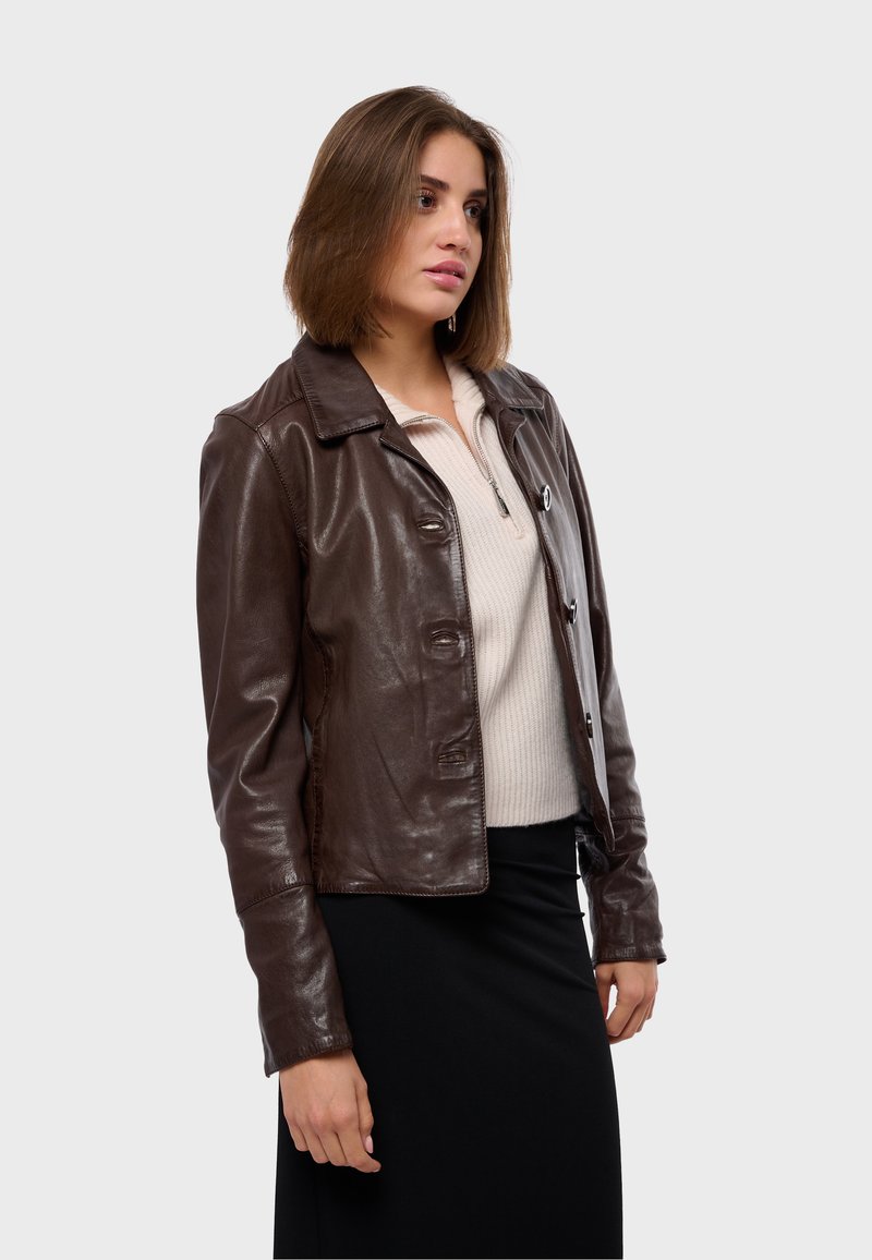 Brązowa skórzana kurtka z kołnierzem, z przodu na guziki i dopasowanym kroju, w połączeniu z beżowym swetrem na zamek.