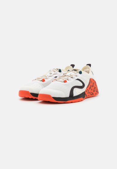 White athletic shoes with a textured upper, black accents, orange soles, and a red leopard print heel detail. Lace-up design with padded collar.