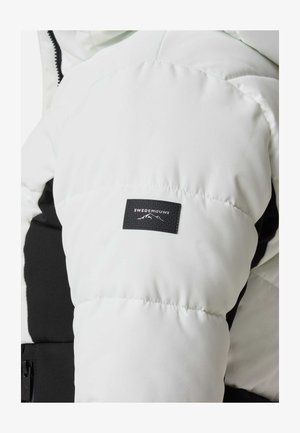 Weißer Puffer-Jacke mit schwarzem Akzent und texturiertem Patch mit "SWEDEMOUNT"-Logo; gestepptes Design, glänzender Stoff und Kapuzenanbringung.