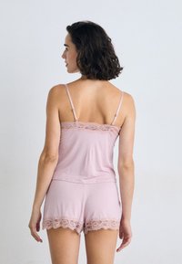 Pink lace-trimmed camisole and shorts set. Soft fabric with delicate lace accents along the hem and neckline. Adjustable straps.