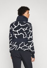 Marinejacke mit weißem abstraktem Muster, hohem Kragen, geripptem Bund, langen Ärmeln und eng anliegenden Ärmeln. Glatter Stoff mit strukturiertem Design.