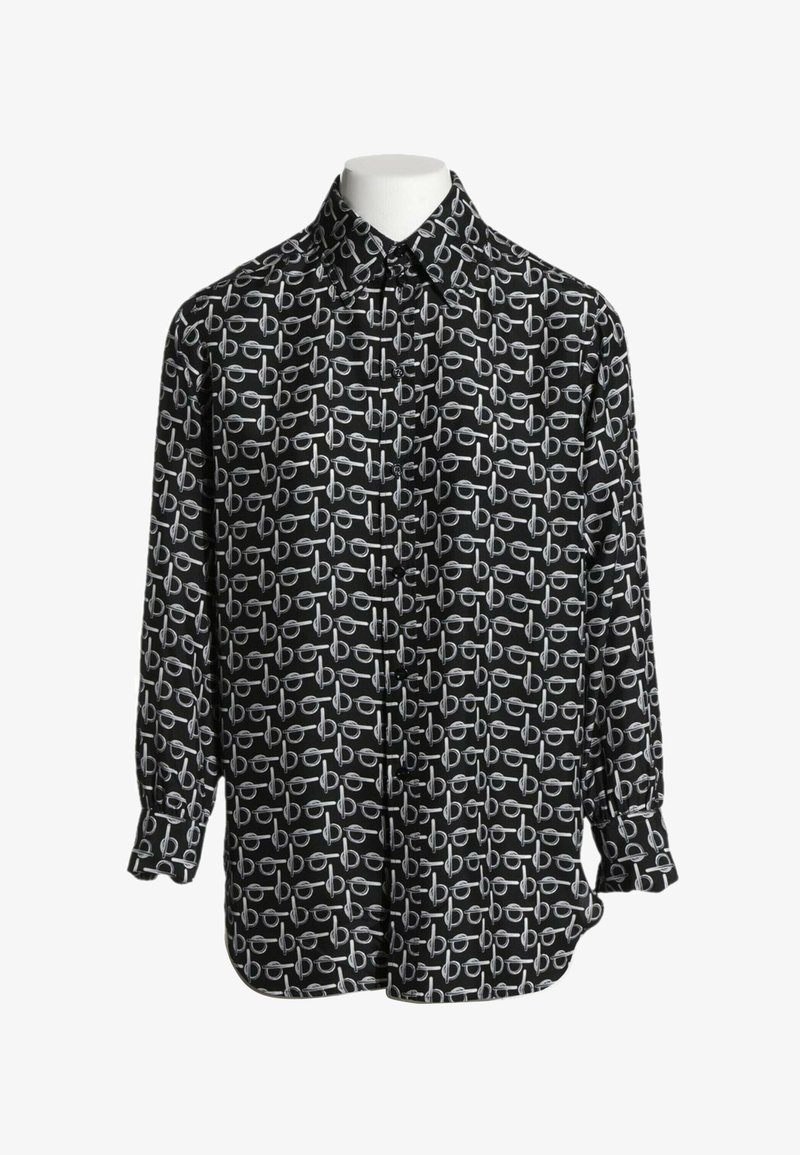 Chemise noire à manches longues avec un motif blanc répétitif de cercles liés et de barres horizontales affichée sur un mannequin sans tête.