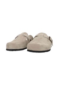 Beige suede clogs with a rounded toe, a side strap and buckle detail, and a black rubber sole, featuring a smooth texture.