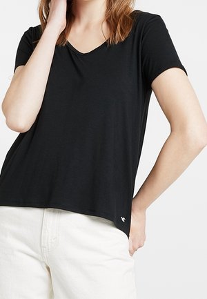 Czarny t-shirt z krótkim rękawem i dekoltem w serek, wykonany z miękkiego materiału. Z drobnym białym logo przy dolnym brzegu.