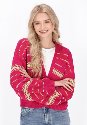 Helderroze gebreide cardigan met V-hals, voorzien van groene en witte geometrische patronen, geribbelde manchetten en een cropped ontwerp.
