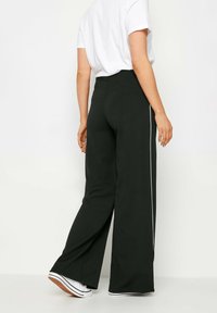 Pantalons noirs à jambes larges en tissu doux avec une taille haute et des rayures blanches sur les côtés. Présente une texture lisse et un design décontracté.