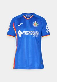 Modrá futbalová dres s vertikálnymi pruhmi, krátkymi rukávmi, okrúhlym výstrihom a farebnými akcentmi v červenej a žltej farbe. Obsahuje logo a branding sponzora.