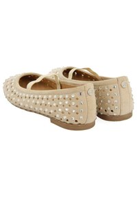 Ballerine beige con tomaia in suede perforata, decorate con borchie argentate, punta tonda e tacco ridotto. Doppie cinghie per un supporto extra.