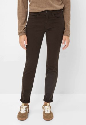 Bruine katoenen jeans met een rechte pasvorm, voorzien van voorzakken en een knoopsluiting. Gecombineerd met bruine sneakers en een beige trui.