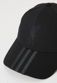 Sort baseball cap lavet af stof med et broderet logo. Har tre mørke striber på skyggen og en struktureret krone.