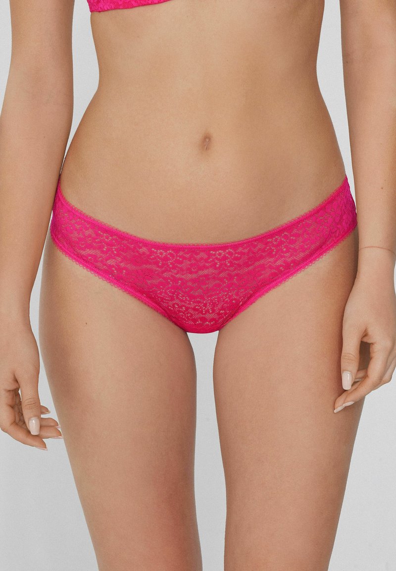 Rosa Spitzen-Bikinislip mit gewelltem Rand, versehen mit einem floralen Muster und elastischem Taillenbund. Sanfte Textur mit kunstvollen Details.