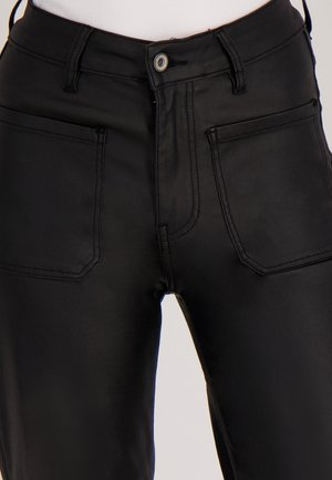 Zwarte hoog uitgesneden broek gemaakt van zachte stof. Voorzien van twee voorkanten zakken, zichtbare steken, en een enkele knoopsluiting.