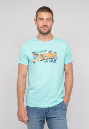 T-shirt vert menthe à manches courtes avec un imprimé graphique « Greetings from Florida » et des accents de palmier. Tissu doux et décontracté.