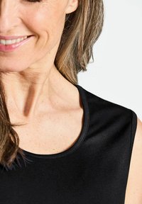 Schwarzes ärmelloses Top mit rundem Ausschnitt. Glatte Textur und schlichtes Design, das das Schlüsselbein und den Schulterbereich betont.