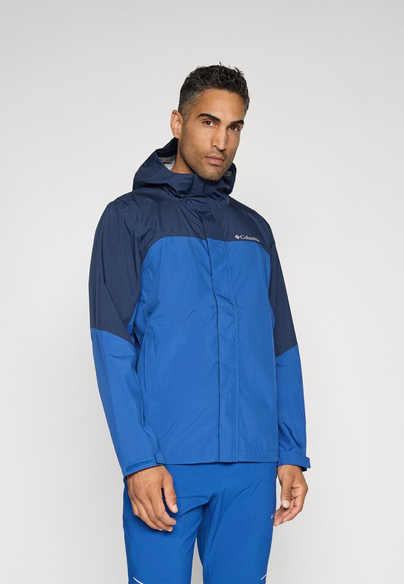 Niebieska wodoodporna kurtka z ciemnoniebieską górną częścią, regulowanym kapturem i gładkim wykończeniem. Posiada szczegóły logo na klatce piersiowej.