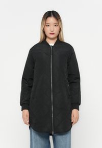 Black quilted long jacket with a zip closure, ribbed cuffs, and side pockets. Features a round neckline and a straight hem.