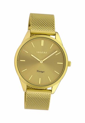 Montre avec un bracelet en mailles dorées, dotée d'un cadran rond minimaliste, d'un cadran soleillé, de marqueurs horaires en bâton et de l'inscription "Vintage" près du bas.