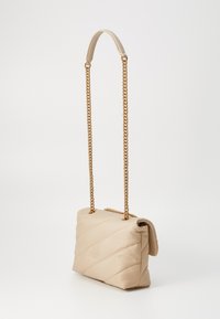 Πετσετέ τσάντα σε μπεζ απόχρωση, φτιαγμένη από λείο υλικό, με αλυσίδα σε χρυσό τόνο και κλείσιμο με καπάκι που έχει διακριτικό ανάγλυφο λογότυπο.