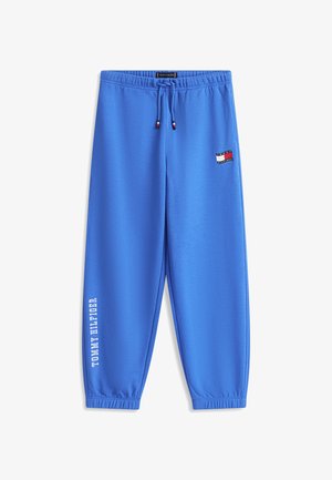 Blå Tommy Hilfiger joggers med elastisk talje og manchetter, snøre, logopatch på hoften og mærkenavn trykt vertikalt på venstre ben.