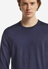 Långärmad marinblå tröja med rund halsringning, tillverkad av mjukt tyg, med en slät textur och enkel design utan mönster eller detaljer.