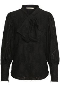 Svart spetsblus med blommönster, långa puffärmar, åtsittande manschetter och en stor knut vid kragen.