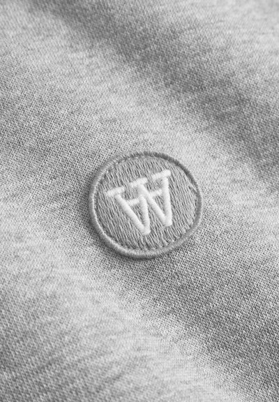 Gray fabric featuring a circular embroidered patch with a stylized "W" in white thread. Smooth texture with subtle fabric detail.