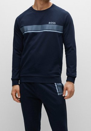 Granatowa bluza z okrągłym dekoltem, z jasnoniebieskim paskowanym wzorem na wysokości klatki piersiowej oraz logo "BOSS" po lewej stronie.