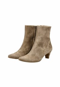 Botas de tobillo de ante beige con punta afilada, cremallera lateral y tacón curvado. La superficie tiene una textura suave y un acabado liso.