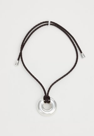 Podesiva ogrlica s poliranim srebrnim okruglim privjeskom, osigurana pletenom smeškom od smeđe boje, završena srebrnim akcentima na krajevima.