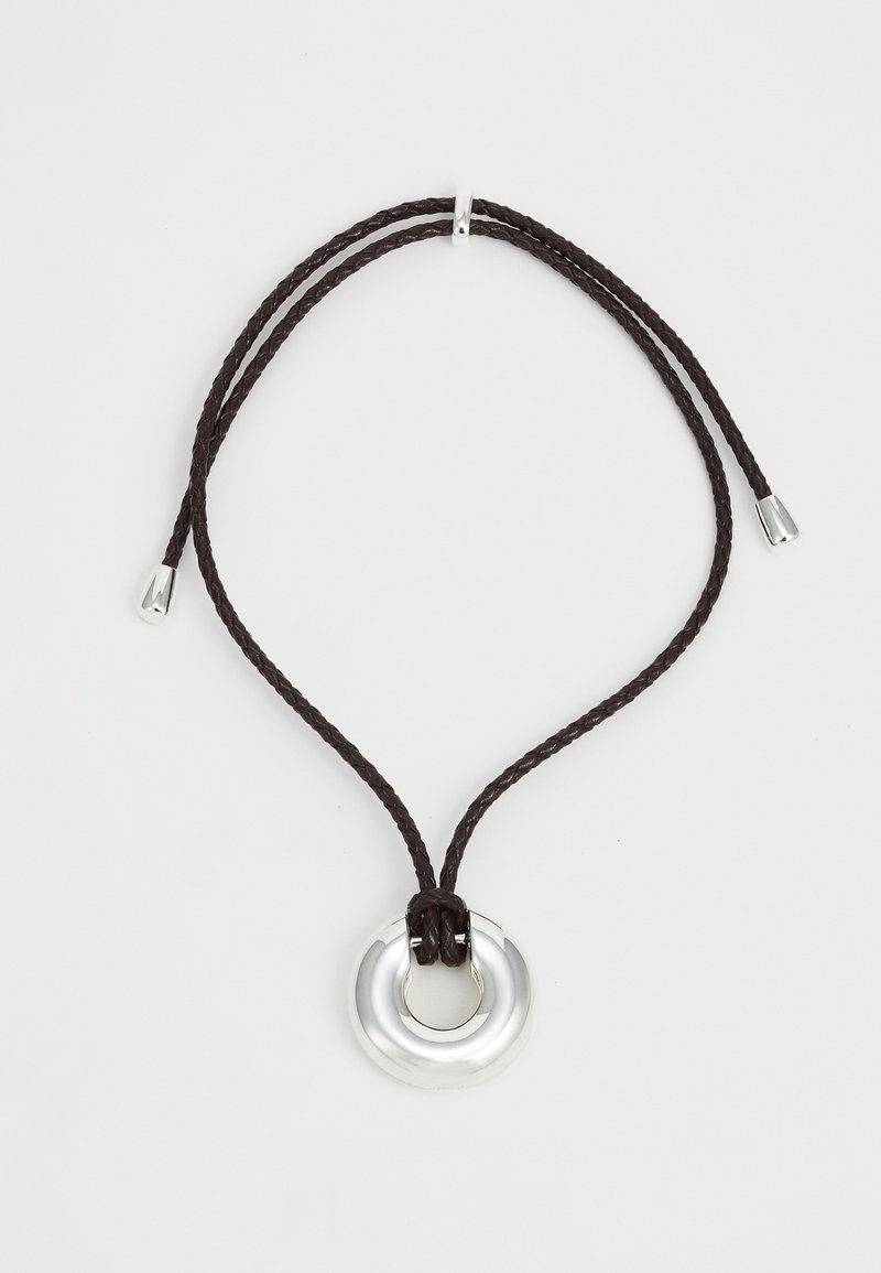 Collana regolabile con pendente circolare in argento lucido, fissata con corda intrecciata marrone, rifinita con accenti in argento alle estremità.