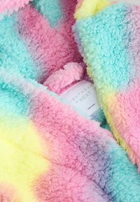 Pastel tie-dye tæppe i blødt, fluffy stof med farverne blå, pink, gul og grøn. Mærket viser "LIGHTWEAR by NEXT."