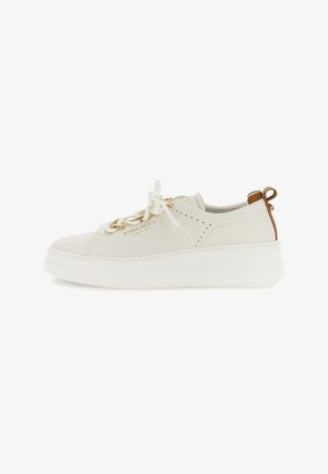Beige lage sneaker met dikke witte zool, gouden kettingdetail op de veters, geperforeerde zijkant en bruine treklus aan de hiel.