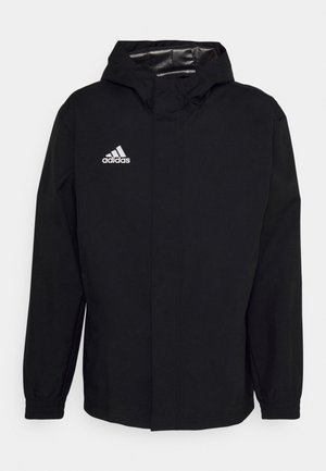Must have mustan kapuutsiga jakk veekindlast materjalist. Sellel on elastsed mansetid, esine tõmblukk ja vasakul rinnal valge Adidas'i logo.