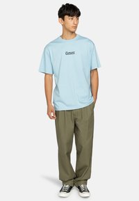 Light blue cotton T-shirt with 'Element' text in black, paired with loose olive-green pants and black-and-white sneakers.