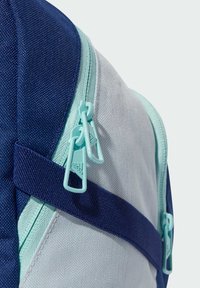 Batoh s kombinací námořnické a světle modré látky, s mátovými zipy, robustními popruhy a strukturovanými povrchy pro lepší úchop.