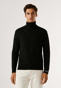 Maglione nero a collo alto in un tessuto a maglia liscia, con un design aderente e polsini a costine con un accento del logo sulla manica.