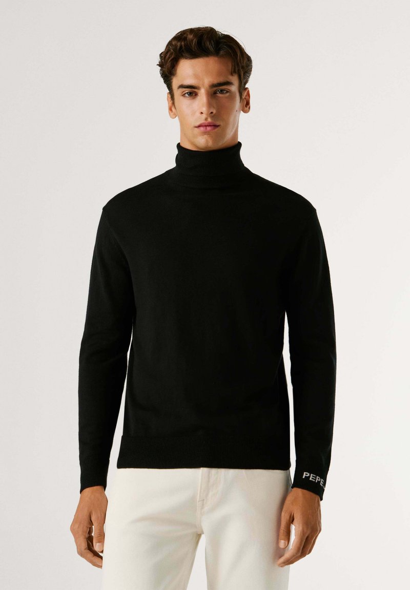 Maglione nero a collo alto in un tessuto a maglia liscia, con un design aderente e polsini a costine con un accento del logo sulla manica.