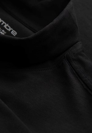 Zwarte katoenen polo met een hoge kraag, met een gladde textuur en subtiele stikdetails. Logo bedrukt aan de binnenkant van de halslijn.