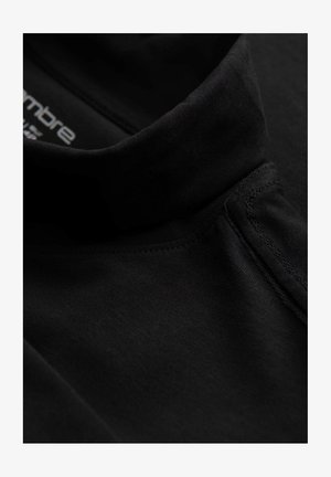 Zwarte katoenen polo met een hoge kraag, met een gladde textuur en subtiele stikdetails. Logo bedrukt aan de binnenkant van de halslijn.