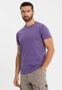 Fialové bavlněné tričko s krátkými rukávy, klasickým kulatým výstřihem a uvolněným střihem. Kombinováno se béžovými cargo šortkami s bočními kapsami.