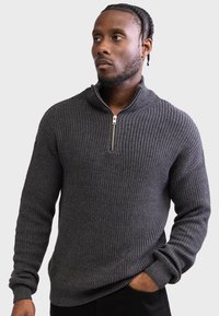 Dark gray zip-up sweater with a ribbed texture, high collar, and gold zipper detail.