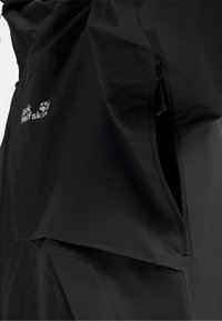 Black Jack Wolfskin Jackensektion zeigt seitliche Reißverschlusstasche teilweise geöffnet und Stofftextur.