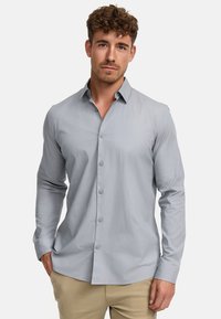 Camisa de botones de manga larga en gris claro, con ajuste slim, que presenta un cuello clásico y cinco botones en la parte delantera. Tejido de algodón suave.