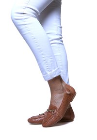 Ciemnobrązowe plecione skórzane mokasyny z niskim obcasem, z akcentem w złotym kolorze. W połączeniu z białymi, podwiniętymi dżinsami skinny.