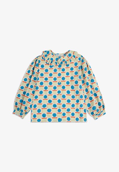 Langarmshirt mit Rüschenausschnitt, das ein blaues und oranges kreisförmiges Muster auf hellgelbem Hintergrund zeigt. Mit Knopfleiste vorne.