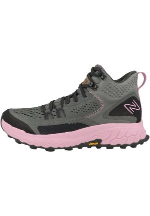 Chaussures de randonnée mi-hautes grises avec accents noirs, semelle rose et tige en textile. Présente des motifs texturés, des lacets et un logo Vibram sur la semelle.