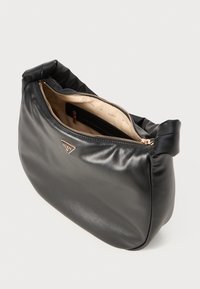 Bolsa de mão preta em couro com uma forma suave e arredondada. Apresenta um fecho com zíper e um forro interior bege com um pequeno bolso com zíper. Detalhe do logótipo visível.