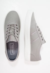 Baskets en toile grises avec semelles en caoutchouc blanches, dotées de lacets ronds, de surpiqûres et d'une étiquette portant la mention "JACK & JONES".